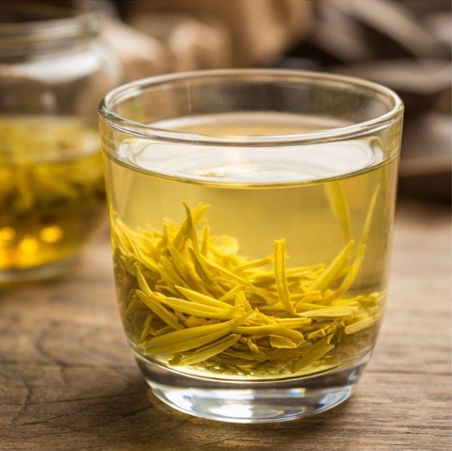 brewing yellow tea in a clear glass cup showing pale golden tea liquor