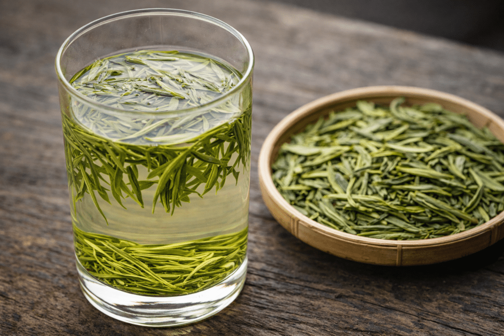 Longjing Dragon Well green tea leaves and freshly brewed tea in a glass cup